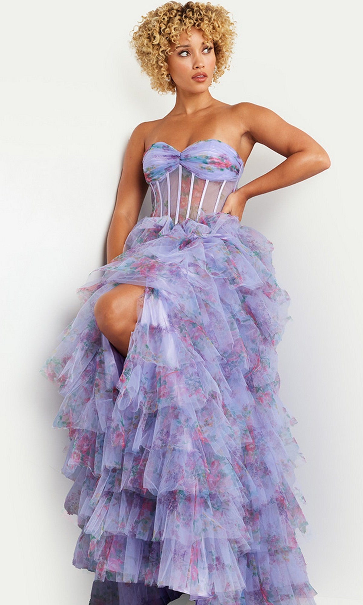 Woman wearing a purple tiered ball gown dress with floral patterns on a white background